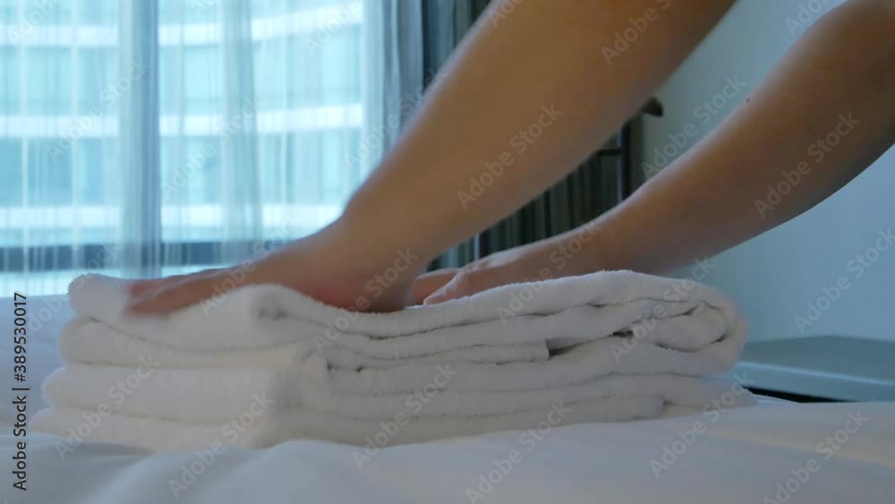 Housekeeper is putting towel on the bed in the room Housekeeper is putting towel on the bed in the room