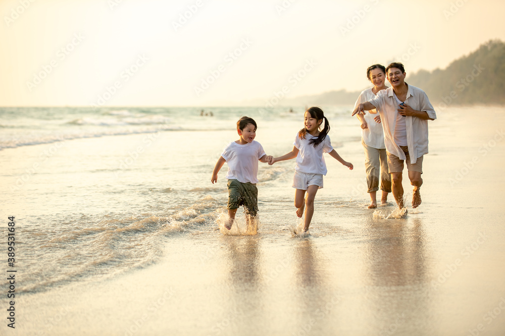 Happy Asian family grandparents with grandchild running and having fun together on the beach in summer day. Grandpa and grandma with kids relax and enjoy summer outdoor lifestyle holiday vacation.