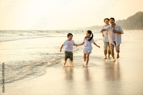 Happy Asian family grandparents with grandchild running and having fun together on the beach in summer day. Grandpa and grandma with kids relax and enjoy summer outdoor lifestyle holiday vacation.