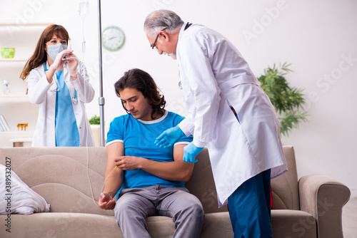 Two doctors visiting sick young man at home