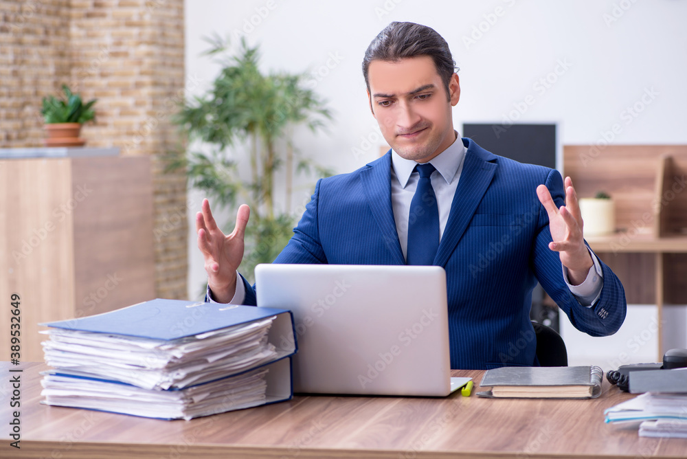Young male employee unhappy with excessive work Young male employee unhappy with excessive work