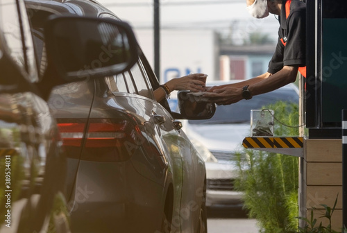 Hand in the car is picking up a personal cup of coffee from the salesman by driving through. Prevention corolona virus or COVID-19.