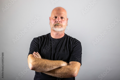 Obraz na plátne Grumpy old man with his arms crossed and stern expression on his gray beard cove