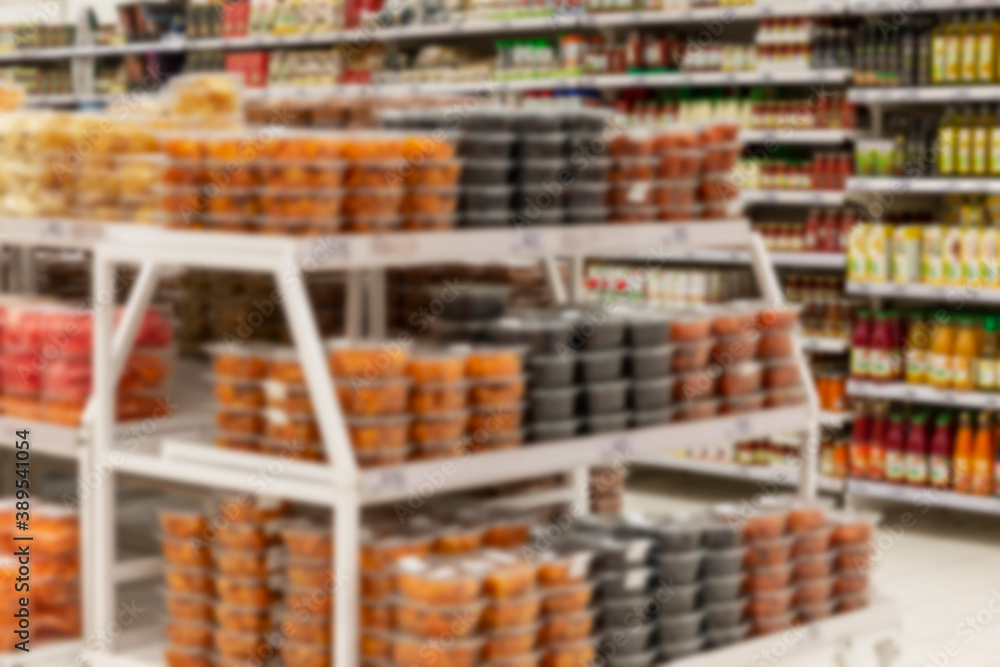 Canned food in jars on the shelves in the supermarket, store interior. Blurred.