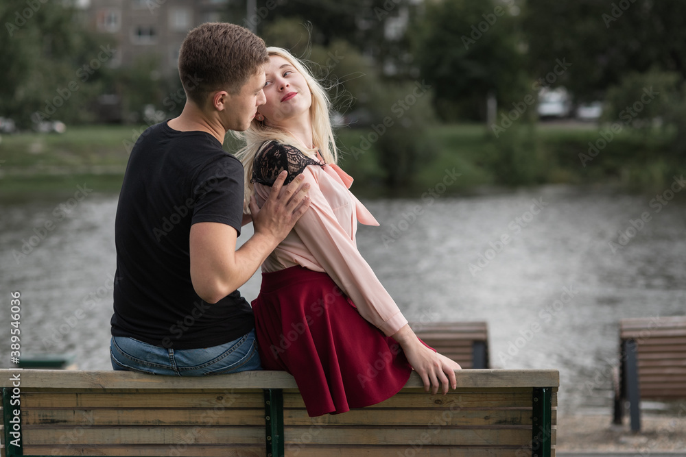 Young couple embrace sitting on wooden bench