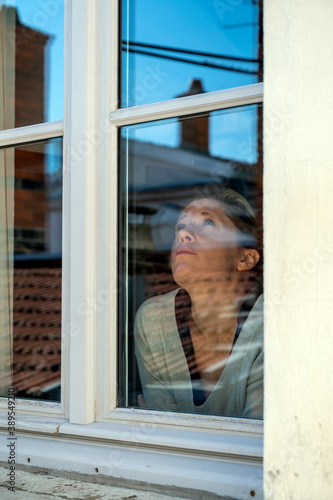 Femme triste confinée derrière une fenêtre fermée