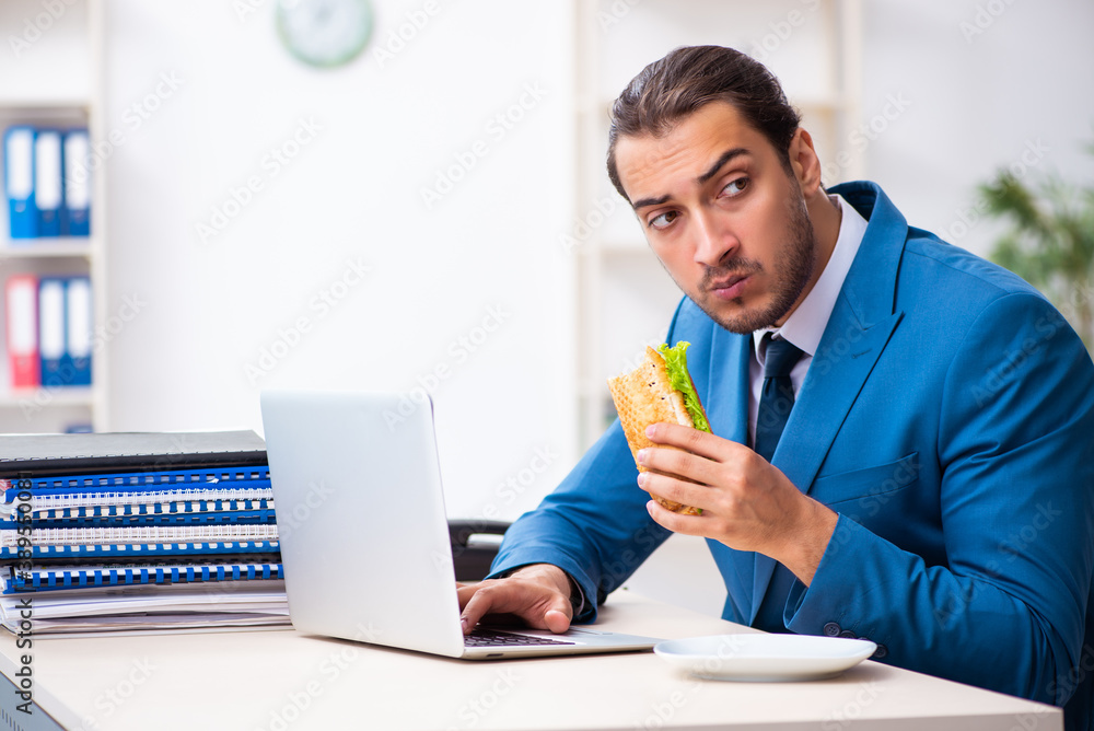 Young male employee having breakfast at workplace Young male employee having breakfast at workplace