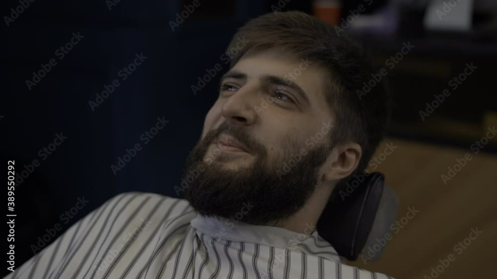 bearded man sitting in a barbershop. Communicates and smiles cheerfully bearded man sitting in a barbershop. Communicates and smiles cheerfully