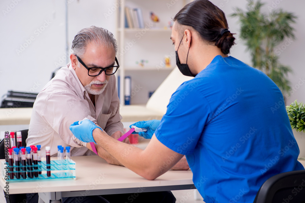 Old patient visiting young male doctor in blood transfusion conc Old patient visiting young male doctor in blood transfusion conc