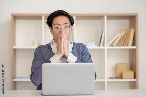 Professional anxiety. Work problem. Bad news. Online conference. Worried asian male employee in glasses looking scared at laptop at light home office.