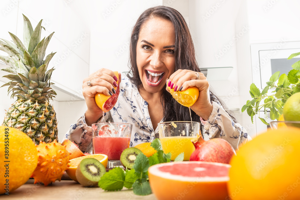 Female squeezing red and yellow orange into a fresh juice Female squeezing red and yellow orange into a fresh juice