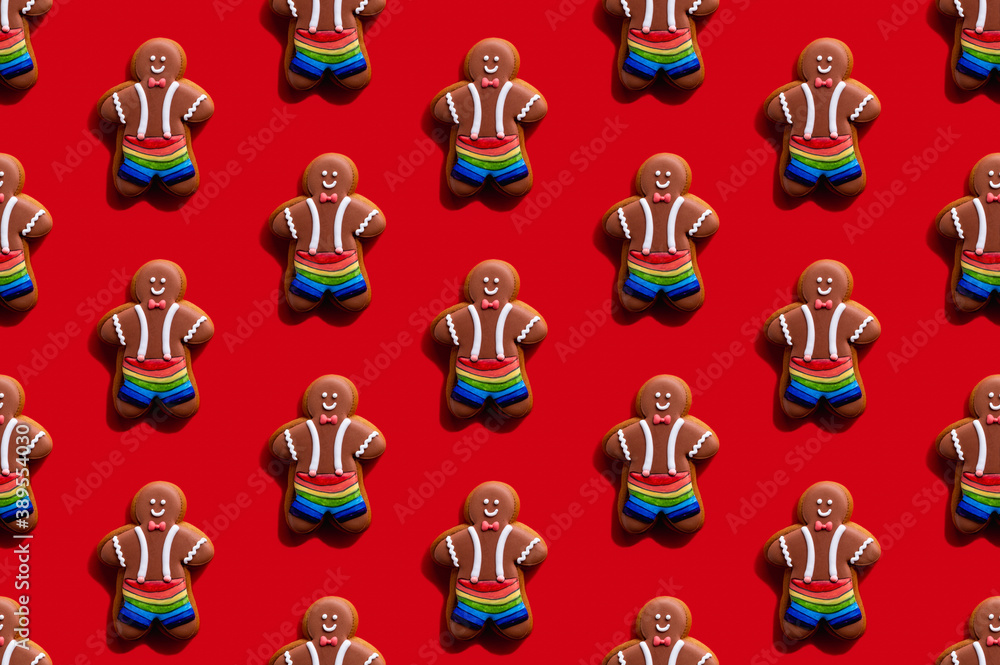 Fototapeta premium Lgbt pride. Red seamless background. Diversity tolerance. Bakery food art conceptual ornament. Happy African gay gingerbread man biscuit in rainbow shorts minimalist composition isolated on bright.