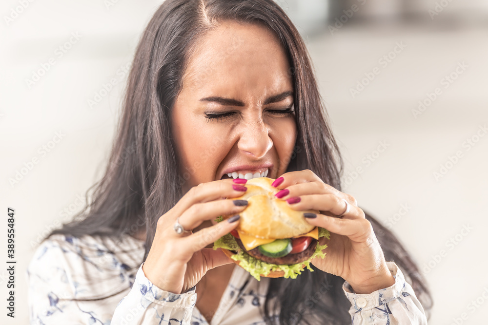 Girl trying to open her mouth as much as possible to bit off a big hamburger Girl trying to open her mouth as much as possible to bit off a big hamburger