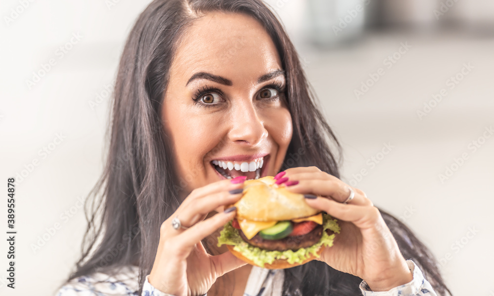 Beautiful woman holding a burger in her hands with a smile