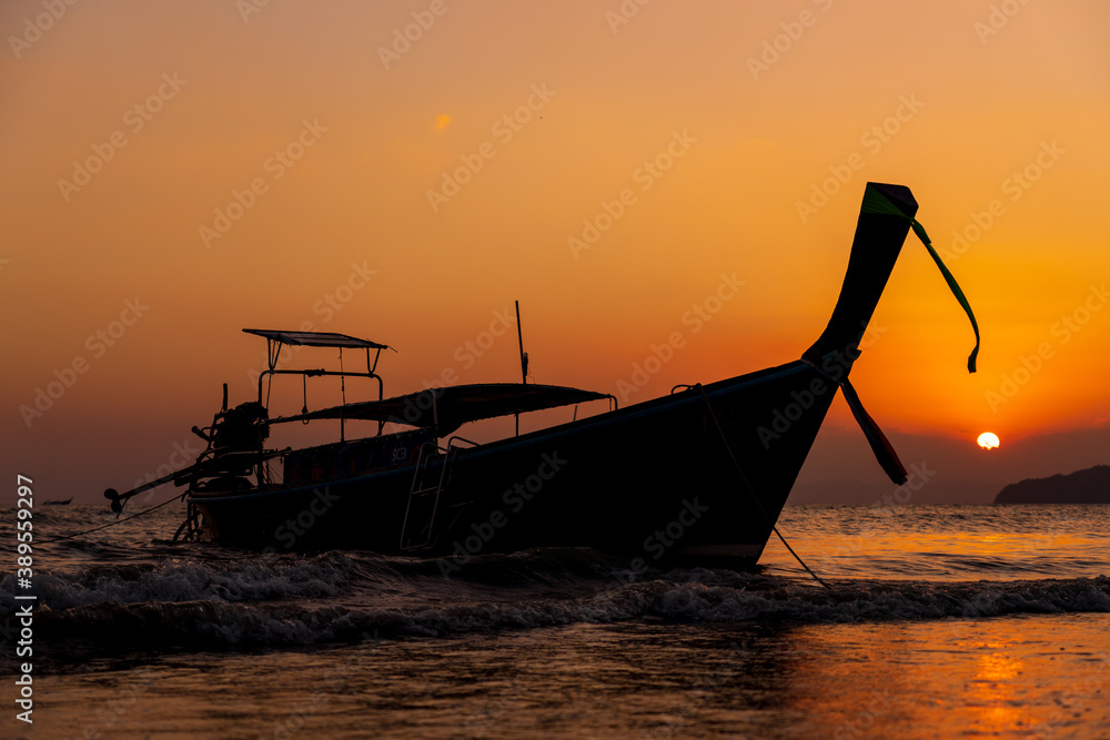 Traditional long-tail boat on the beach in Thailand at sunset