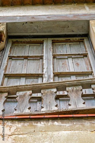 cracked ruin with a damaged window with closed wooden shutters and a cracked wall