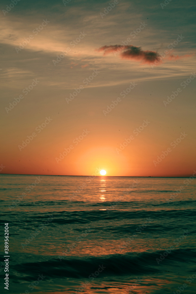 sunrise over the mediterranean sea with little  cloud on the clear sky, yellow sun with gradient sunrise color, vertical image , location martil morocco tetouan