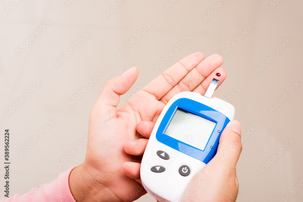 Closeup Hands woman measuring glucose test level check with blood on finger by glucometer at home she monitor and control high blood sugar diabetes and glycemic health care concept Closeup Hands woman measuring glucose test level check with blood on finger by glucometer at home she monitor and control high blood sugar diabetes and glycemic health care concept