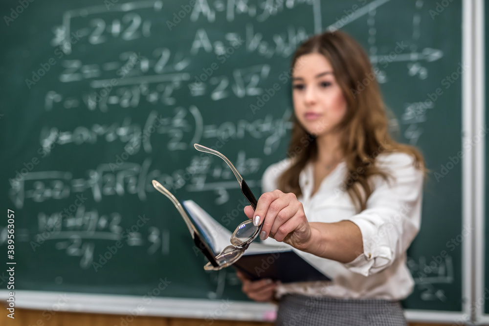Beautiful caucasian woman teacher standing in classroom near chalkboard Beautiful caucasian woman teacher standing in classroom near chalkboard