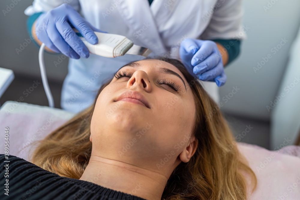 female doctor using device for ultrasonic facial doing client face peeling procedure female doctor using device for ultrasonic facial doing client face peeling procedure