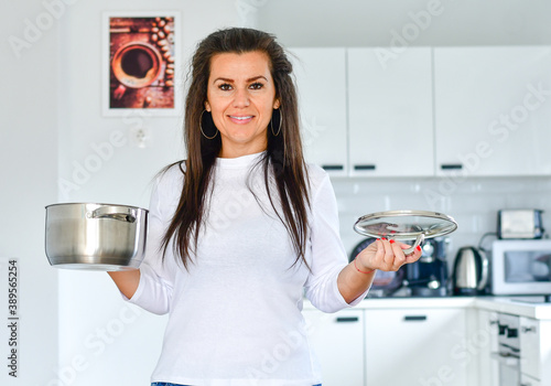 Young smiling woman at home cooking at the kitchen. Eating home made food at winter time