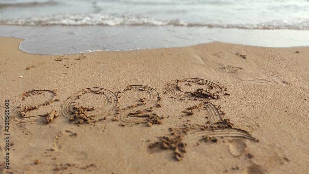 Obraz premium handwritten inscription 2020 and 2021 on sand of sea beach.