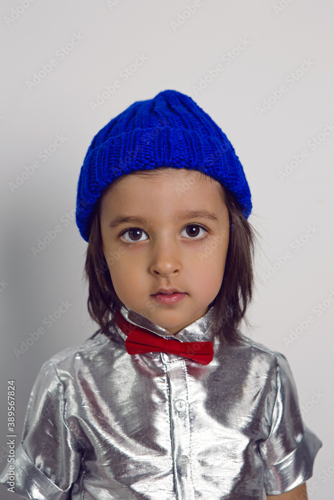 portrait boy child in a blue knitted hat and silver shirt red bow tie on the background in the Studio portrait boy child in a blue knitted hat and silver shirt red bow tie on the background in the Studio