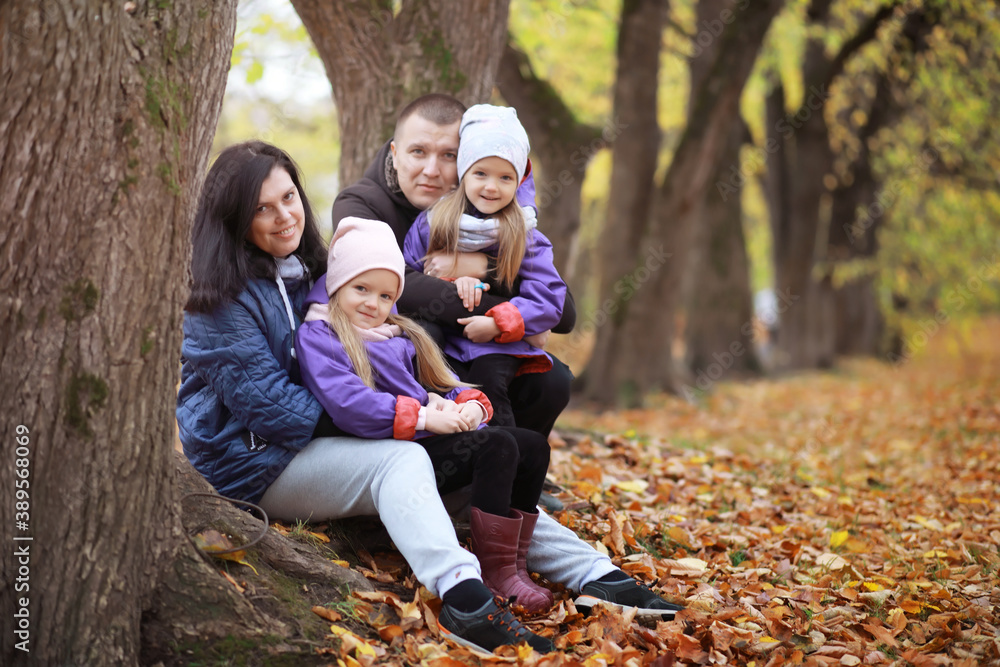 Young family on a walk in the autumn park on a sunny day. Happiness to be together.