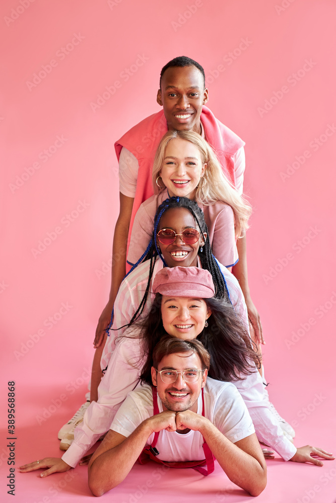 portrait of positive group of diverse people in a row down up, they laugh, isolated pink background