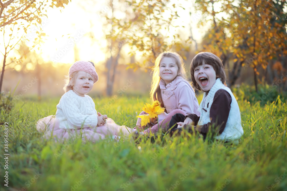 Fototapeta premium Young family on a walk in the autumn park on a sunny day. Happiness to be together.