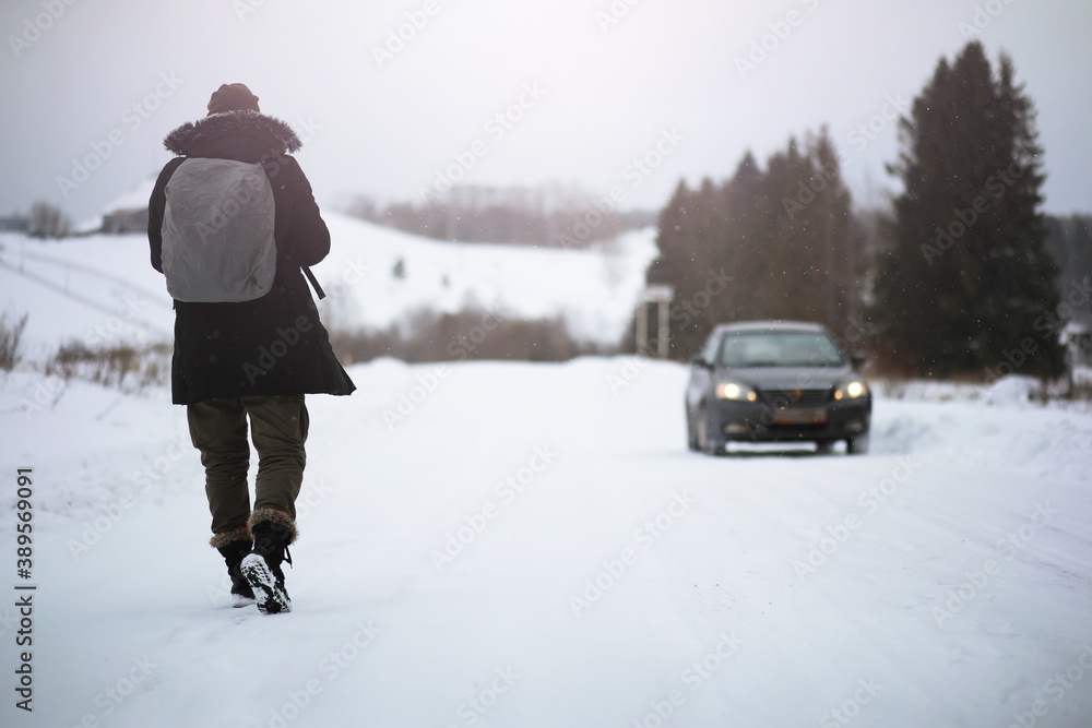 A man in winter clothes on the street. Tourists travel through the snowy country. On the way, walk and hitchhike. A man in winter clothes on the street. Tourists travel through the snowy country. On the way, walk and hitchhike.