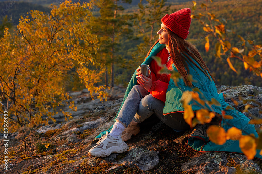 young female traveller sits enjoying hot tea on mountains,have a warm after hiking, wearing warm clothes, in contemplation young female traveller sits enjoying hot tea on mountains,have a warm after hiking, wearing warm clothes, in contemplation