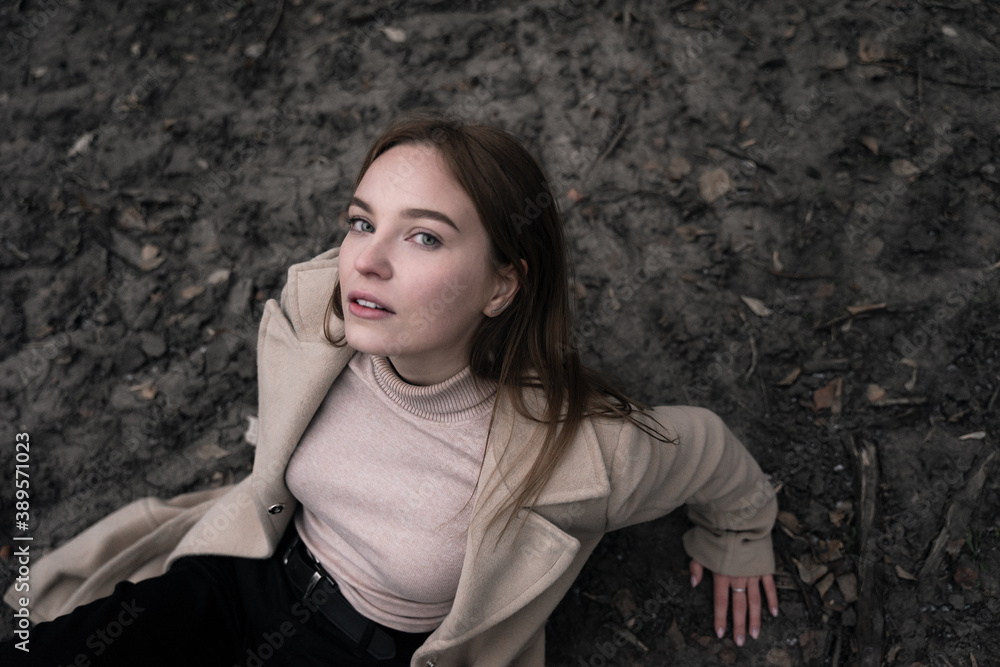 a beautiful girl sits on the ground, leaning on her hands, her head thrown back, looks into the camera, top view, a sensual look a beautiful girl sits on the ground, leaning on her hands, her head thrown back, looks into the camera, top view, a sensual look