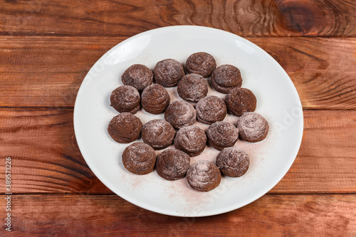 Chocolate truffles on white dish on the rustic table