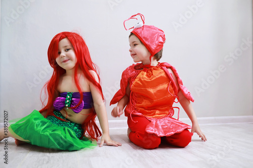 Children in smart carnival costumes on a plain background. Costume of sea fairy creatures. Mermaid and crab. photo