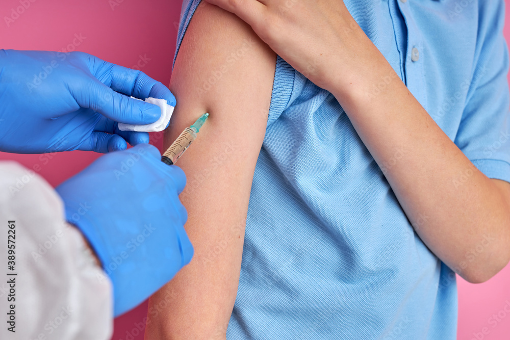 close up of doctor hand using syringe to make vaccine injection to cropped child boy patient, isolated on pink background close up of doctor hand using syringe to make vaccine injection to cropped child boy patient, isolated on pink background