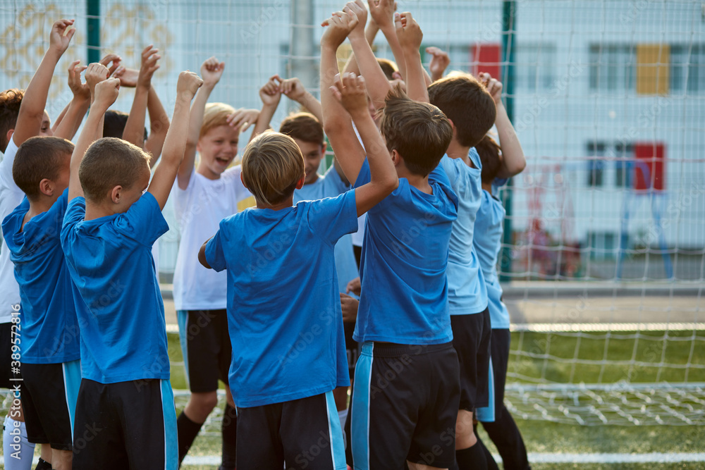 Fototapeta premium little kid boys celebrate the winning, congratulate each other, wearing uniform. rear view on football team