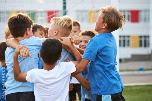 Tablou pe pânză cheerful boys have fun after winning in football game, young kids hug each other