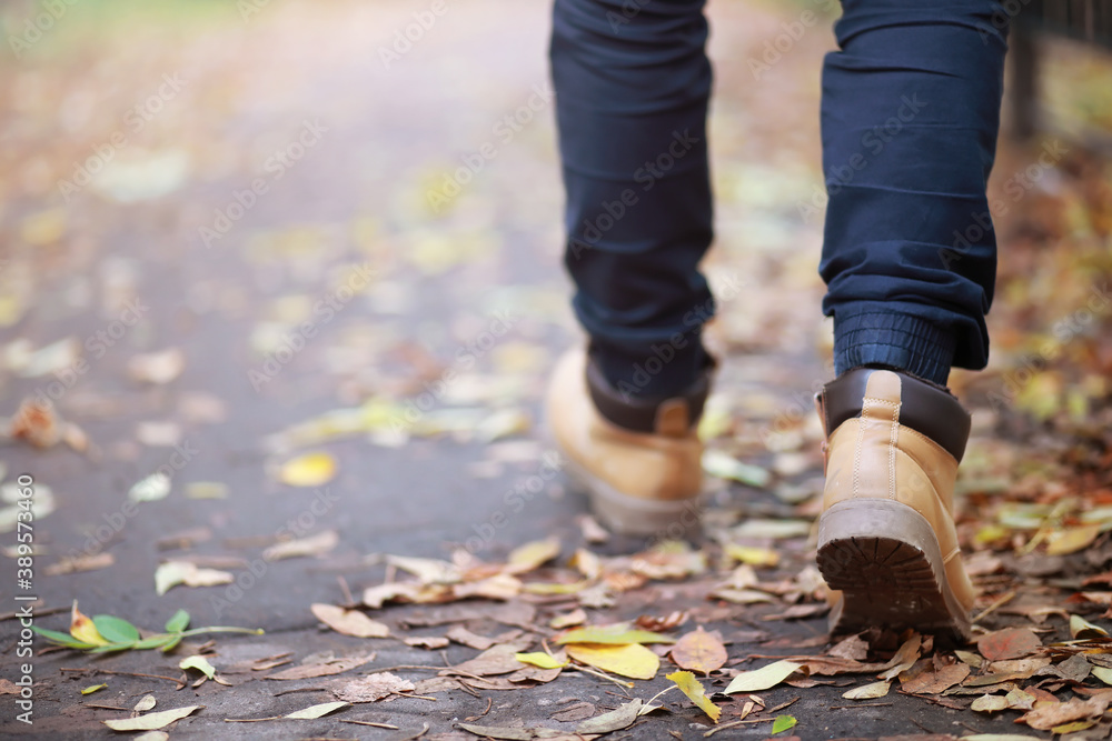 Autumn concept. Pedestrian feet on the road. Autumn leaves on the footpath. Autumn concept. Pedestrian feet on the road. Autumn leaves on the footpath.
