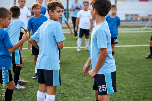 two boys discuss football game in stadium, two players have talk, they divided into 2 groups