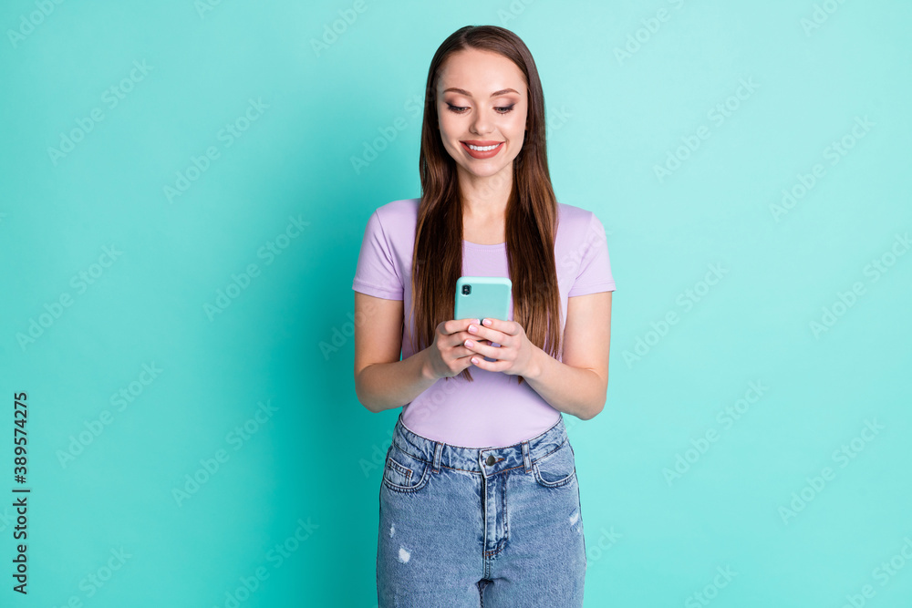 Photo portrait of girl keeping smartphone reading using app smiling isolated on vibrant teal color background Photo portrait of girl keeping smartphone reading using app smiling isolated on vibrant teal color background