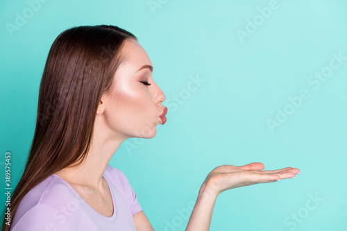 Side profile photo of girl sending air kiss with closed eyes isolated on bright teal color background with copyspace