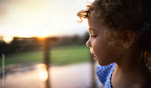 Close-up portrait of small girl outside at dusk, holiday in nature concept.