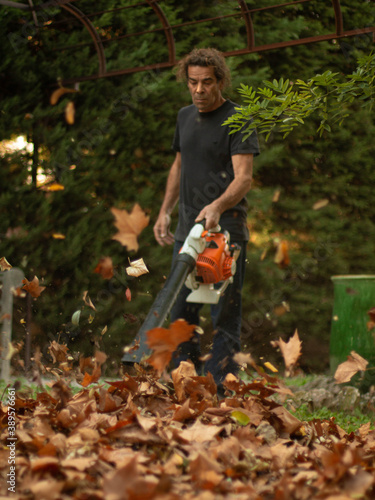 Un homme passe le soufflant dans son jardin, pour rassembler les feuilles tombées de l'automne? photo