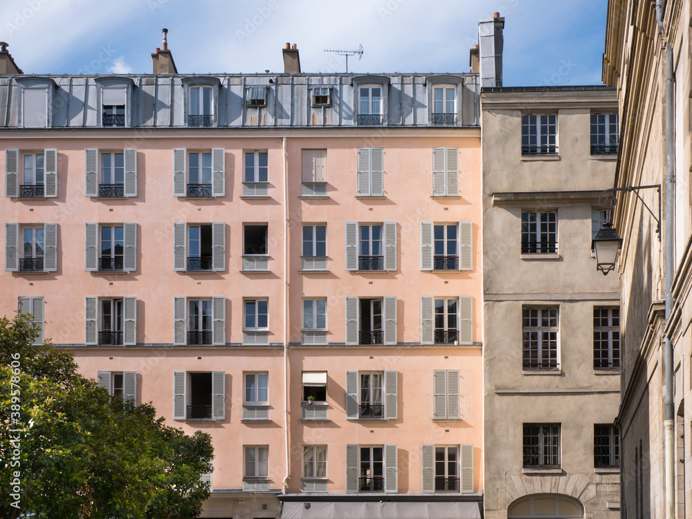 Fototapeta premium Architecture in Paris, Blue sky and white clouds, roof and attic room, low-angle shot, historic front buildings windows, artistic view of the city center