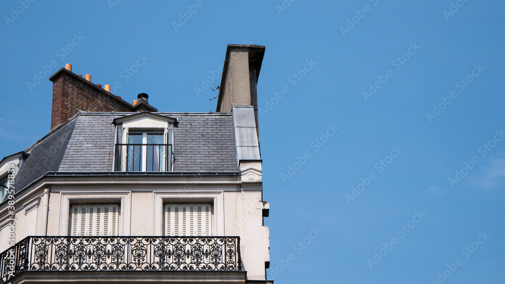 Haussmann architecture in Paris, Blue sky and white clouds, roof and attic room, low-angle shot of facade, front buildings perspective, historic center, artistic view of the city, balcony