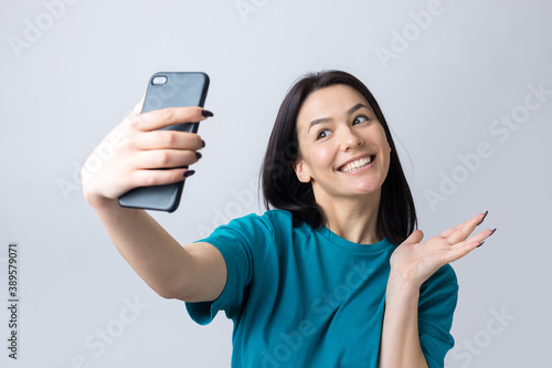 Portrait of a pretty girl taking a selfie isolated over grey background