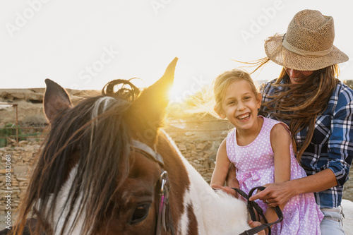 Happy family mother and daughter having fun riding horse inside ranch © Alessandro Biascioli