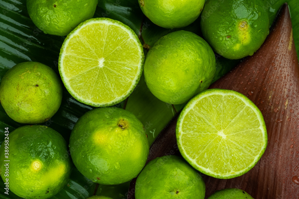 Pile of half and whole fresh lime juicy on green banana leaves with clearly water drop on surface Pile of half and whole fresh lime juicy on green banana leaves with clearly water drop on surface