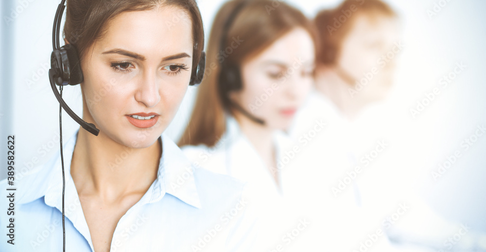 Call center operators. Focus on beautiful business woman using headset Call center operators. Focus on beautiful business woman using headset